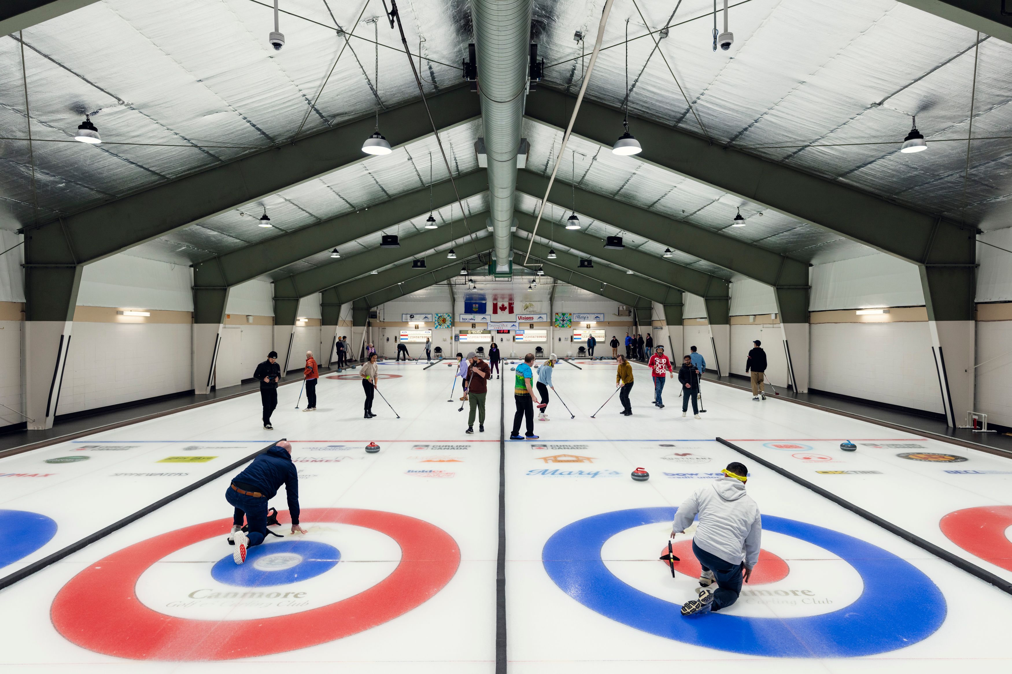 a group of people are playing curling in a large indoor rink .