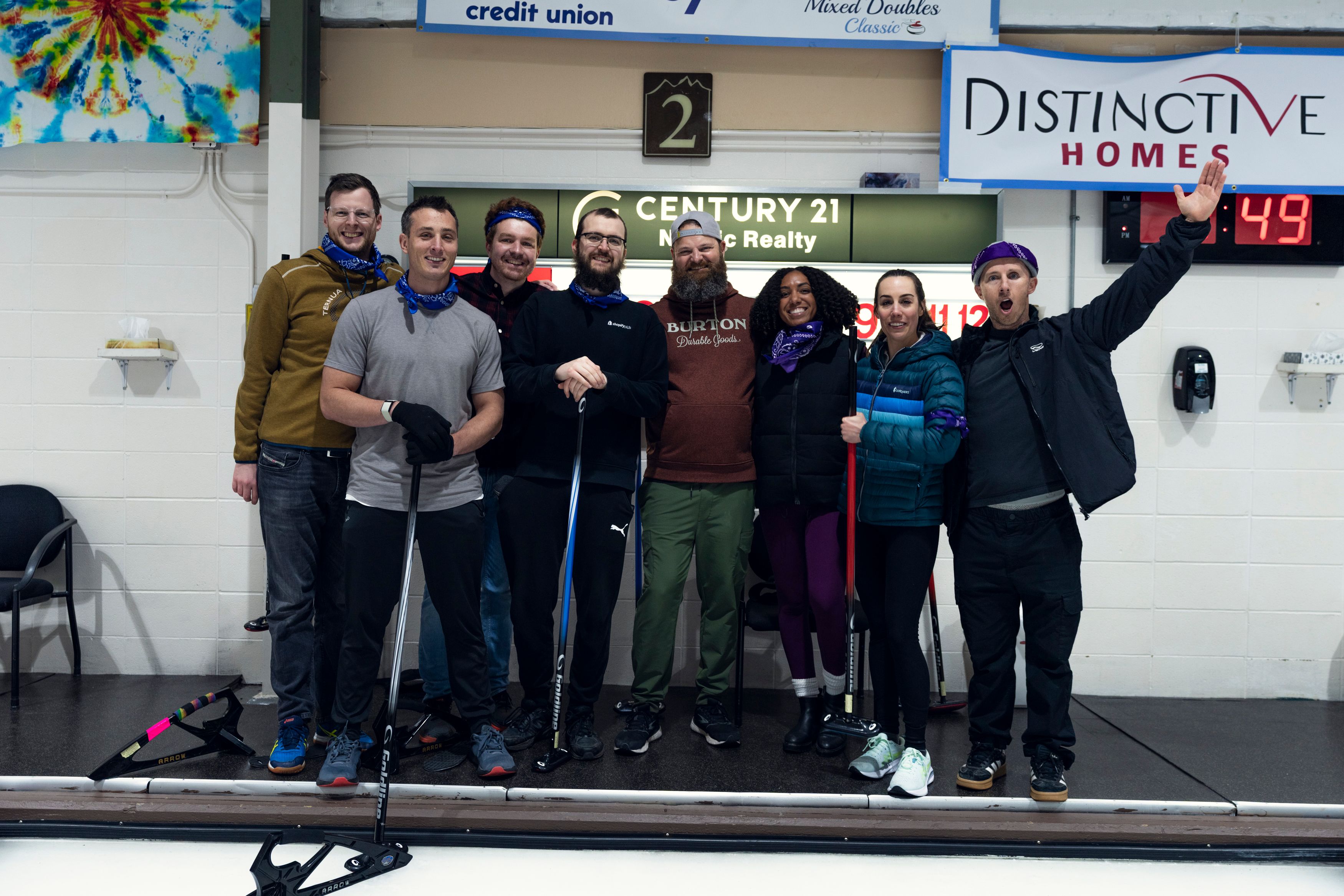 a group of people are posing for a picture on a curling rink .