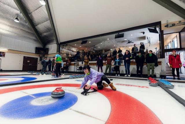 a group of people are playing curling on a rink .